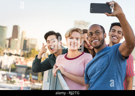 Gruppo di amici prendendo selfie con lo skyline della città in background Foto Stock