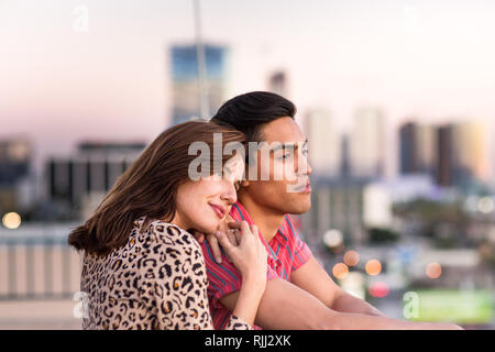 Giovane adulto giovane guardando fuori attraverso lo skyline della città Foto Stock