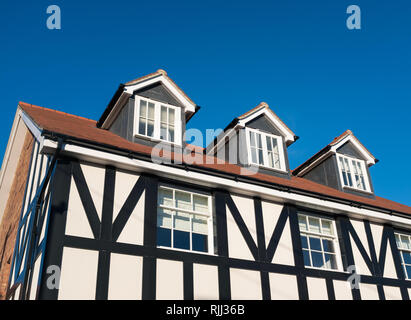 Tre finestre dormer nel tetto di un stile Tudor in bianco e nero Inglese casa residenziale contro un cielo blu. La casa dispone di finestre a ghigliottina e feltro morbido Foto Stock