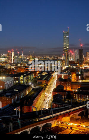 Il centro città di Manchester skyline vista sui tetti delle case da Salford dal bacino di Wilburn, mostrando Beetham Tower guardando giù Liverpool Road di notte Foto Stock