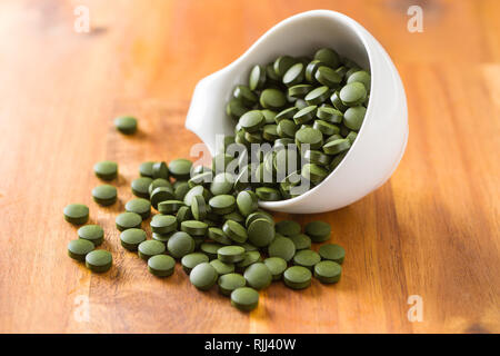 Verde chlorella pillole o orzo verde pillole nel recipiente. Foto Stock