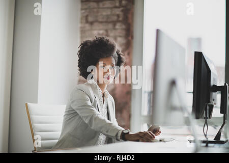 Ritratto di una donna africana di american business executive lavora in un ufficio su un computer desktop Foto Stock