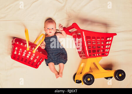 Aiutando a mamma. Ritratto di felice piccolo bambino. Sweet Little baby. La vita nuova e la nascita. Carrello spesa. Padrone di casa. La famiglia. Prodotti per la cura del bambino. Piccola ragazza andare Foto Stock