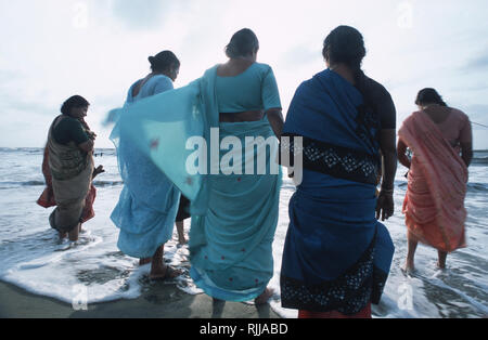 Le signore indiane vestite di saris si tuffano nelle fresche acque marine della costa del Malabar. Foto Stock