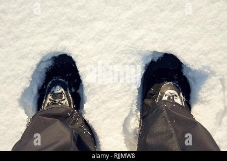 Piano superiore vista laici di piedi in impermeabile stivali inverno nella neve fresca, pantaloni neri, copia bianca di sfondo spazio, nuovo anno risoluzione sport concept Foto Stock