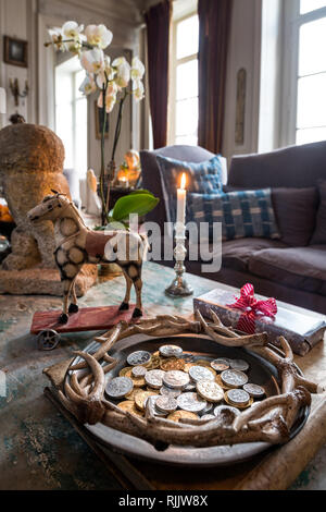 I soldi di cioccolato e giocattoli d'epoca con candela accesa sul tavolo da caffè Foto Stock