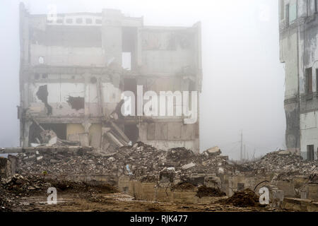 I resti del distrutto il fondamento dell'edificio in forma di pile e le macerie da un mucchio di frammenti di calcestruzzo di pietre sullo sfondo Foto Stock