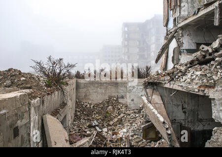 I resti del distrutto il fondamento dell'edificio in forma di pile e le macerie da un mucchio di frammenti di calcestruzzo di pietre sullo sfondo Foto Stock