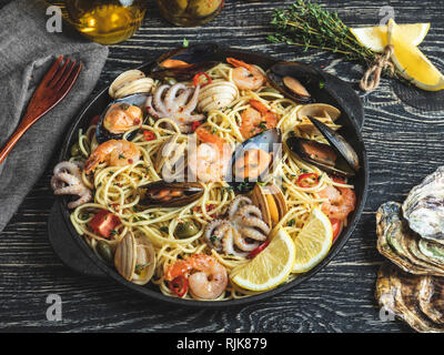 La pasta cotta con vongole, gamberetti, polipetti, cozze pomodoro su una padella , spaghetti. Close up Foto Stock