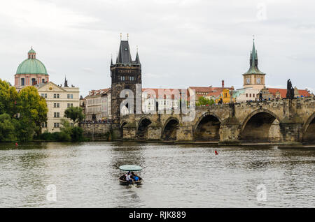 I turisti in una barca sul fiume Vltava nella parte anteriore del ponte Carlo e la torre del ponte della Città Vecchia di Praga, Repubblica Ceca Foto Stock