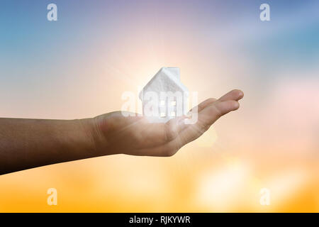 Concetto di ipoteca dalla nuova piccola casa in mano hanno raggi di sole fantastico e alloggiamento di una famiglia giovane o di protezione della proprietà, in vendita o in affitto, mod Foto Stock