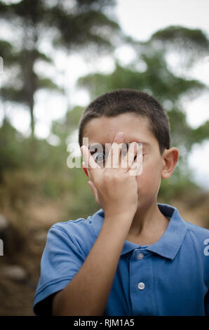 Spaventata ragazzo cerca attraverso la mano Foto Stock