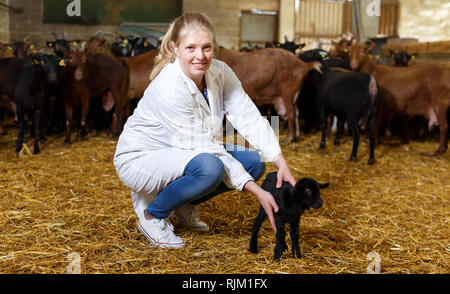 Ritratto di donna qualificata veterinario lavorando su caprini farm, cercando dopo poco capre Foto Stock