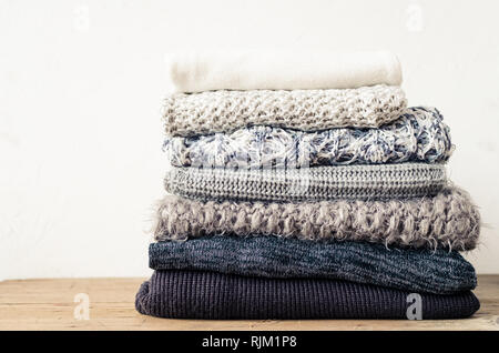 Pila di maglia maglioni di lana. Gradiente monocromatica sfumature di grigio nero bianco colori vestiti con diversi modelli di maglia piegata in pila. Coz caldo Foto Stock