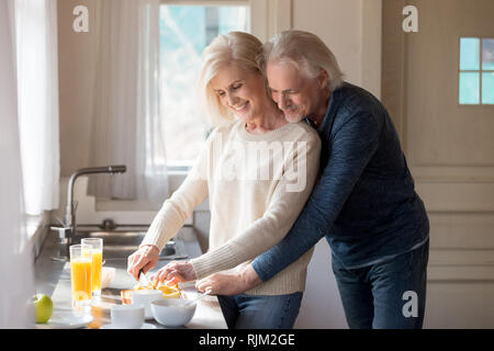 Amare attraente coppia matura prepara la colazione insieme Foto Stock