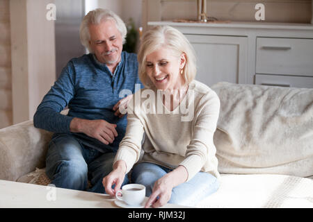 Coppia di mezza età seduta sul lettino in appoggio bere il tè Foto Stock