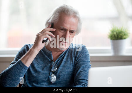 Senior insoddisfatta uomo parlando al telefono cellulare Foto Stock