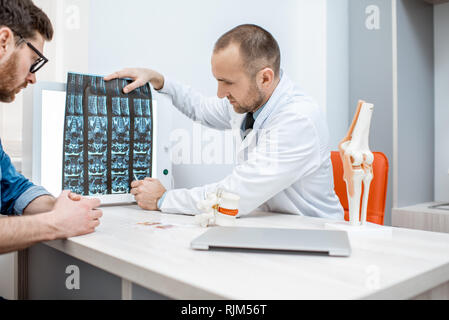 L'uomo durante la consultazione medica con i senior terapista cerca su tomografia stampa in ufficio Foto Stock