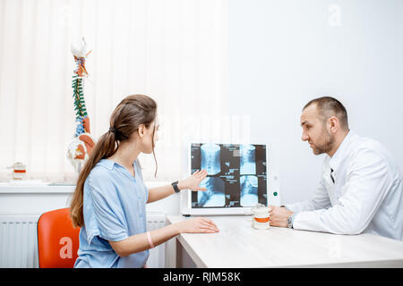 Giovane donna durante la consultazione medica con i senior terapista cerca su tomografia stampa in ufficio Foto Stock