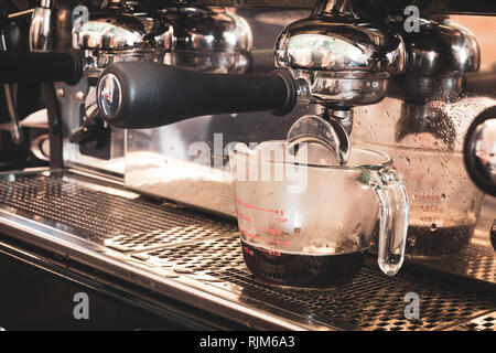 Macchina per caffè prepara il tè verde in tazza bianca. Foto Stock