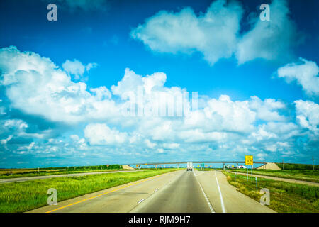 La guida verso il basso che lungo, Lonesome Highway con infinite big sky e nuvole nel piatto paesaggio del Texas Foto Stock