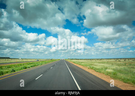 La guida verso il basso che lungo, Lonesome Highway con infinite big sky e nuvole nel piatto paesaggio del Texas Foto Stock