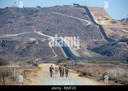 Forze armate USA i soldati in verde di mimetizzazione militare a piedi vicino a doppio strato fissato internazionale muro di confine tra gli Stati Uniti e il Messico Foto Stock