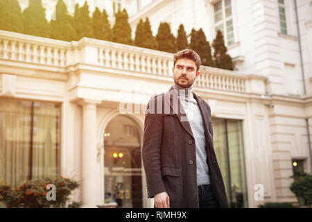 Fiducioso e elegante uomo in piedi fuori nella parte anteriore di un hotel o di un bel vecchio edificio Foto Stock