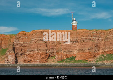 Le rocce rosse con il faro sulla offshore Helgoland isola nel mare del Nord Foto Stock