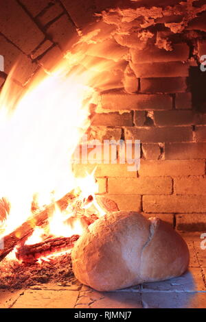 La legna brucia in un vecchio forno per la cottura del pane Foto Stock