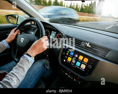 Maiorca, Spagna - 8 Maggio 2018: Shot dall'interno della vettura della donna alla guida di automobile giù strada rurale in estate con Apple cruscotto di automobile le icone del display app Foto Stock