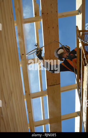 Tradesman verniciatura a spruzzo la parete del legno di un edificio industriale con il preservante del legno Foto Stock