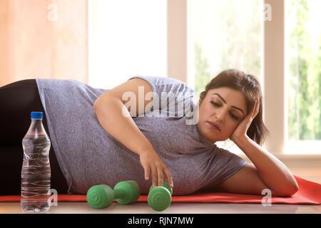 Lazy triste Donna sovrappeso sdraiato sul pavimento e non vuole esercitare Foto Stock