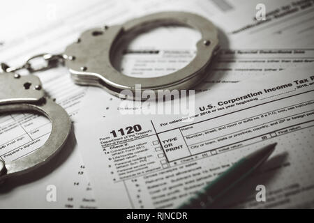 Evasione fiscale concetto - modulo fiscale 1120 e manette Foto Stock