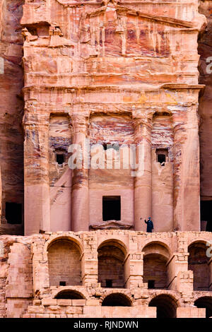 Un uomo di scattare foto di fronte a un enorme tempio scavato nella roccia di Petra. Foto Stock