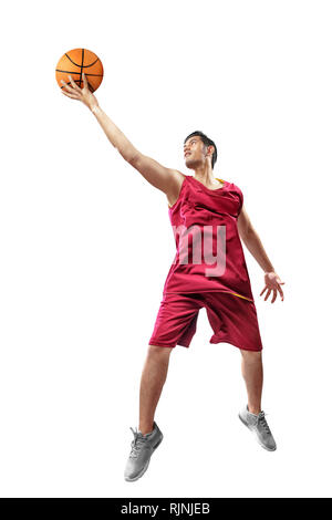 Attraente asian giocatore di basket uomo in uniforme rosso salta con sfera in mani isolate su sfondo bianco Foto Stock