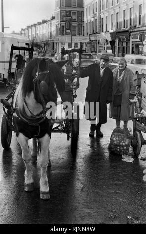 Rag e osso l'uomo con sua moglie partner e il suo cavallo e carrello. Ella ha una strada del mercato di vendita di stallo di verdure fresche. Notting Hill area del West London 1970. La raccolta dei rottami di riciclaggio di riutilizzazione degli anni settanta UK. HOMER SYKES Foto Stock