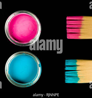 Rosa e blu Paint Pots con pennelli per dipingere su un Backgorund nero Foto Stock
