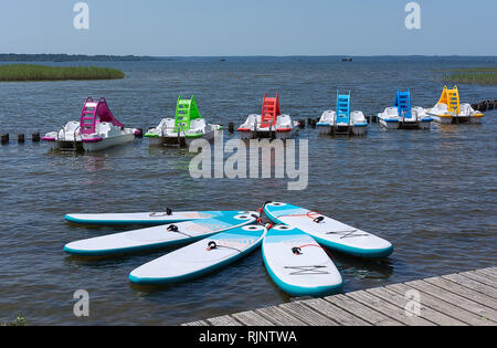 Scheda per Stand Up Paddle Surf Sup e colorate barche a pedali con acqua scorre sulla superficie dell'acqua del lago. Giornata di sole. Foto Stock