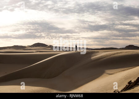 Un uomo in piedi sul deserto cercando il cielo nell'oasi di Siwa Foto Stock