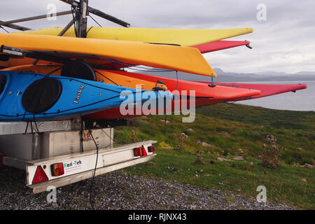 Colorato kayak caricato su un rimorchio di grandi dimensioni su una traccia nella selvaggia campagna aperta in attesa di essere utilizzati in mare aperto Foto Stock