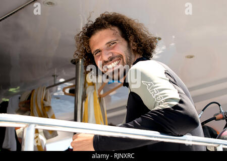 Ritratto di un attraente sorridente curly-dai capelli uomo su un yacht. Una bella subacqueo. Foto Stock