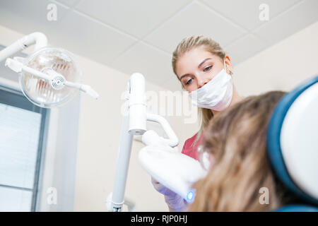 Bella donna dentista fare lo sbiancamento dei denti in studio dentistico Foto Stock