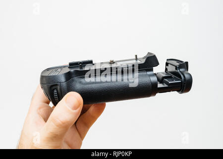 Fotografo mano azienda contro uno sfondo bianco di una fotocamera batteria presa per la sua nuova fotocamera mirrorless o DSLR Foto Stock