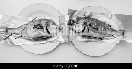 Ampia immagine di due orata pesce orate sul foglio di alluminio sul tavolo bianco - vista dal di sopra od deliziosi piatti fatti in casa - torna e bianco Foto Stock
