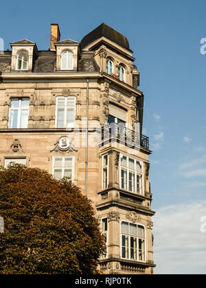 Da sotto il colpo di un bellissimo edificio esterno con balconi e ornamenti sulla parete di pietra sotto il cielo blu a Parigi, Francia Foto Stock