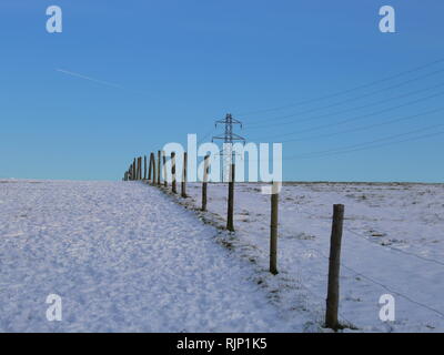 Pali da recinzione attraverso un campo in un paesaggi innevati a Dunstable Downs, Bedfordshire, England, Regno Unito Foto Stock