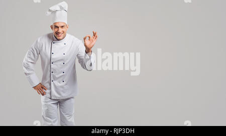 Lo Chef in un bianco uniforme fa un gesto. Foto Stock