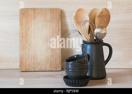 Stoviglie e utensili clayware e diverse cose sul piano portapaziente in legno. Cucina vita ancora come sfondo Foto Stock