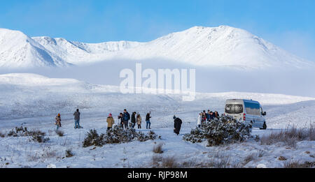 Visitatori, turisti, persone a godersi il paesaggio invernale su un minibus tour. Loch Tulla Viewpoint, A82 road avvicinando Rannoch Moor, Scozia. Foto Stock